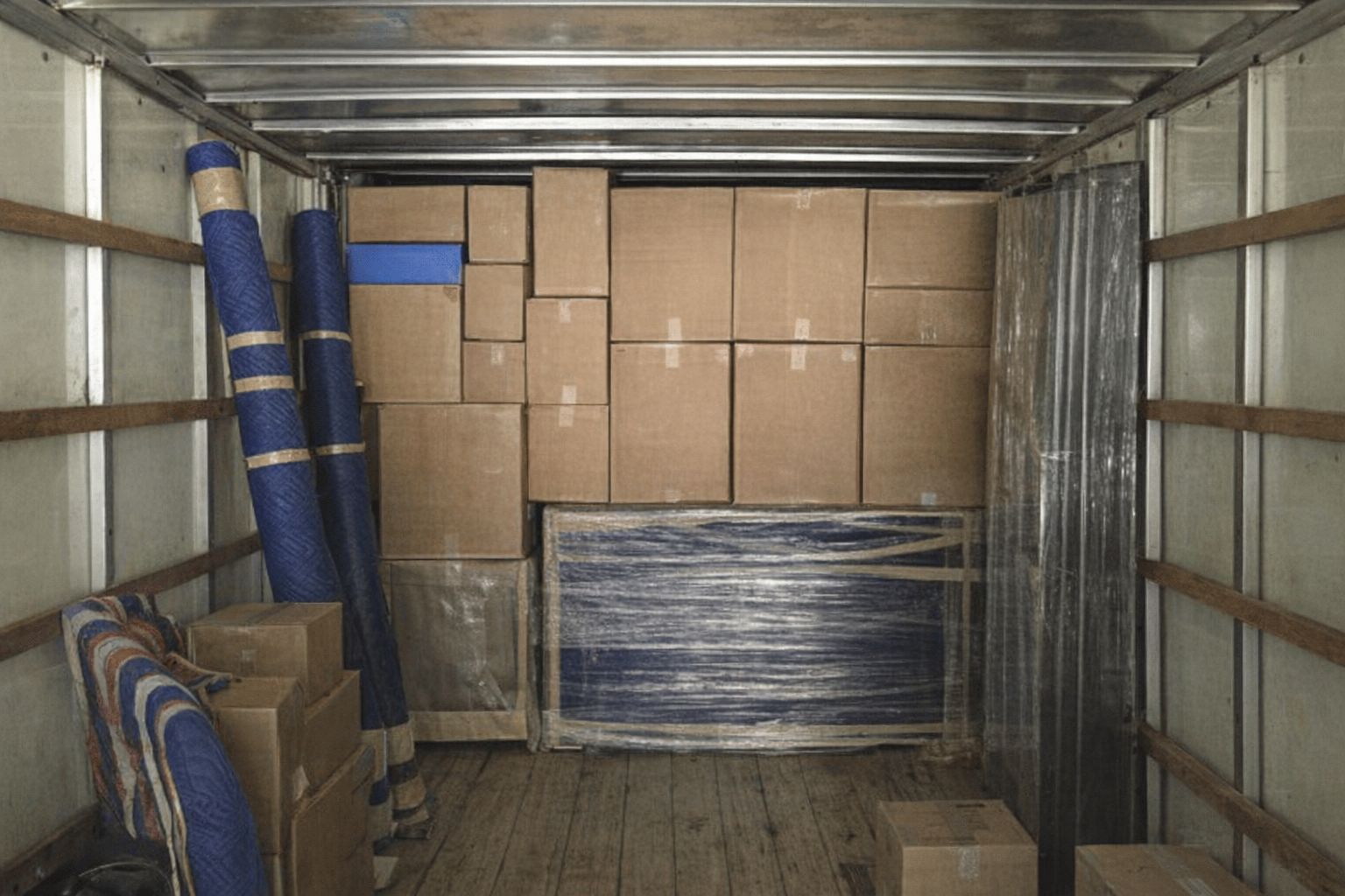 Blick in einen beladenen Transporter mit Umzugskartons und Equipment.